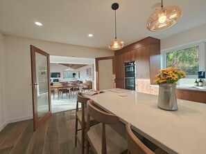 A modern kitchen with a large island, wooden cabinets, and a dining area with a view. - 5 Bed in Tealby (oc-t30618) (Tealby)