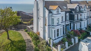 A row of Victorian-style houses with bay windows, a grassy yard, and a view of the sea.