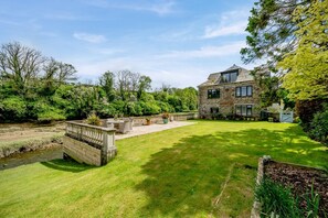 A stone house with a well-maintained lawn and a small pond. - 2 Bed in Little Petherick (oc-o30788) (Little Petherick)