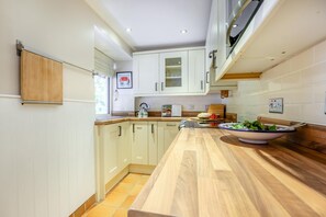 Eine moderne Küche mit weißen Schränken, einer Holzauskleidetheke und einer Salat-Schüssel auf der Arbeitsfläche.