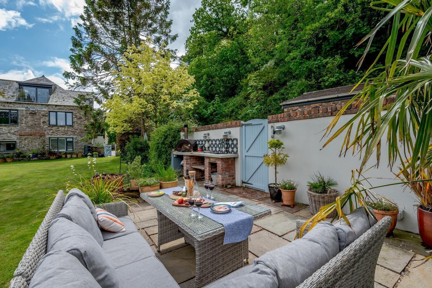 A patio area with outdoor furniture, a barbecue grill, and a stone building in the background.