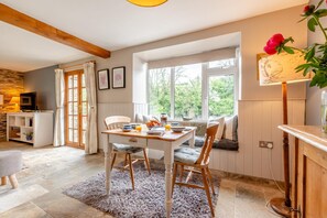 A cozy dining area with a wooden table, chairs, and a view of greenery outside.