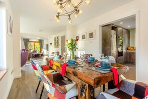 A dining area with a wooden table set for six, colorful chairs, and a modern chandelier. - 3 Bed in Letter Finlay (oc-l30952) (Altura)