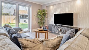 Een moderne woonkamer met een bank, een salontafel, een televisie en een groot raam.