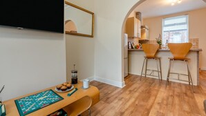 Een moderne keuken met een houten aanrecht, twee barkrukken en een koffiehoek.