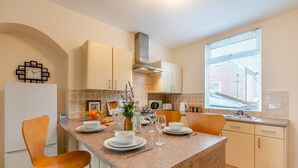 Een moderne keuken met een centraal eiland, witte kastjes en een raam met zonwering.