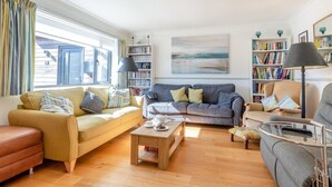 A cozy living room with a sofa, a coffee table, and a bookshelf. - 4 Bed in Ringstead (oc-k30839) (Ringstead)