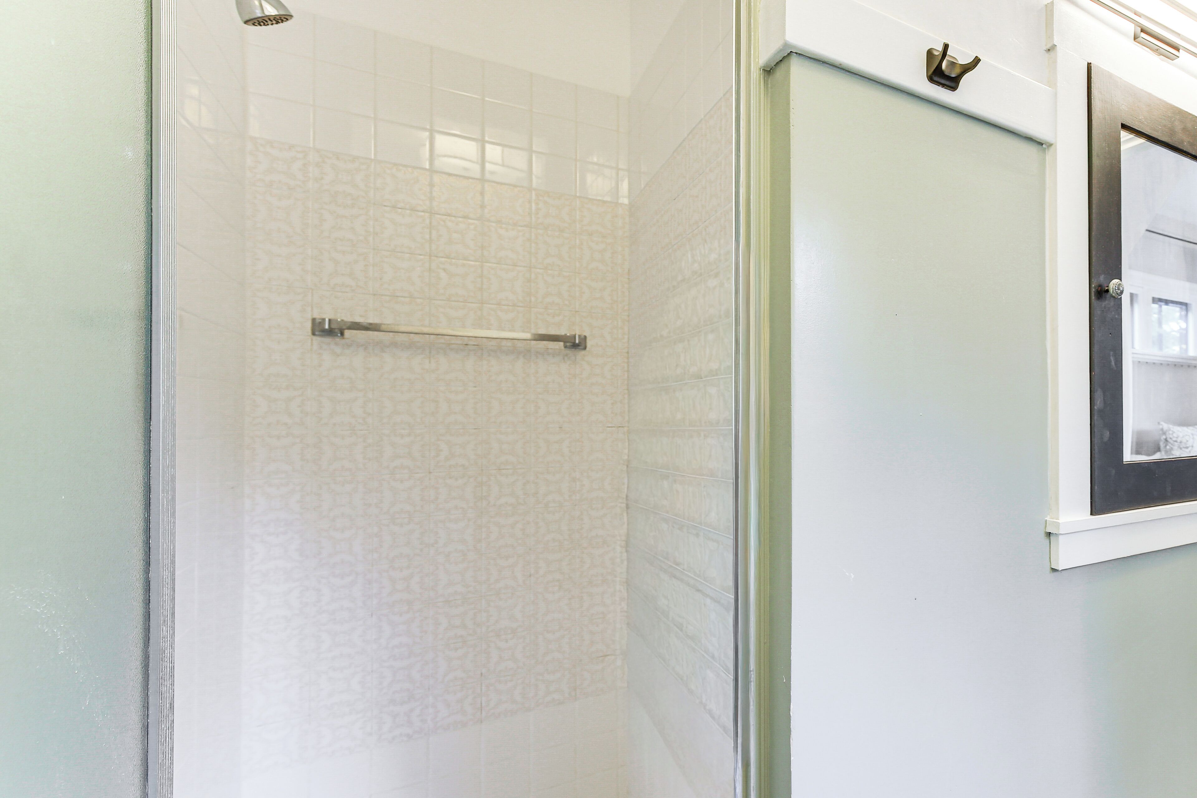 A bathroom with a glass shower enclosure, a towel rack, and a framed picture on the wall.