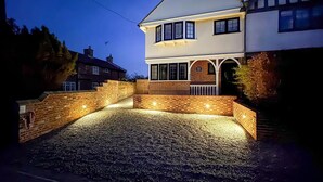 A two-story house with a driveway, brick walls, and a well-lit entrance. - 5 Bed in Walberswick (oc-m30723) (Walberswick)