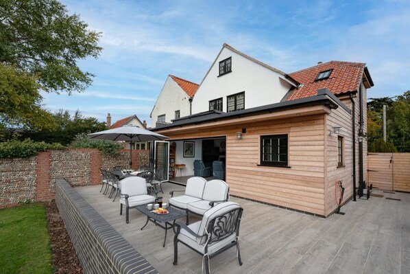 Et toetagers hus med terrasse, udendørs møbler og en murstensvæg.