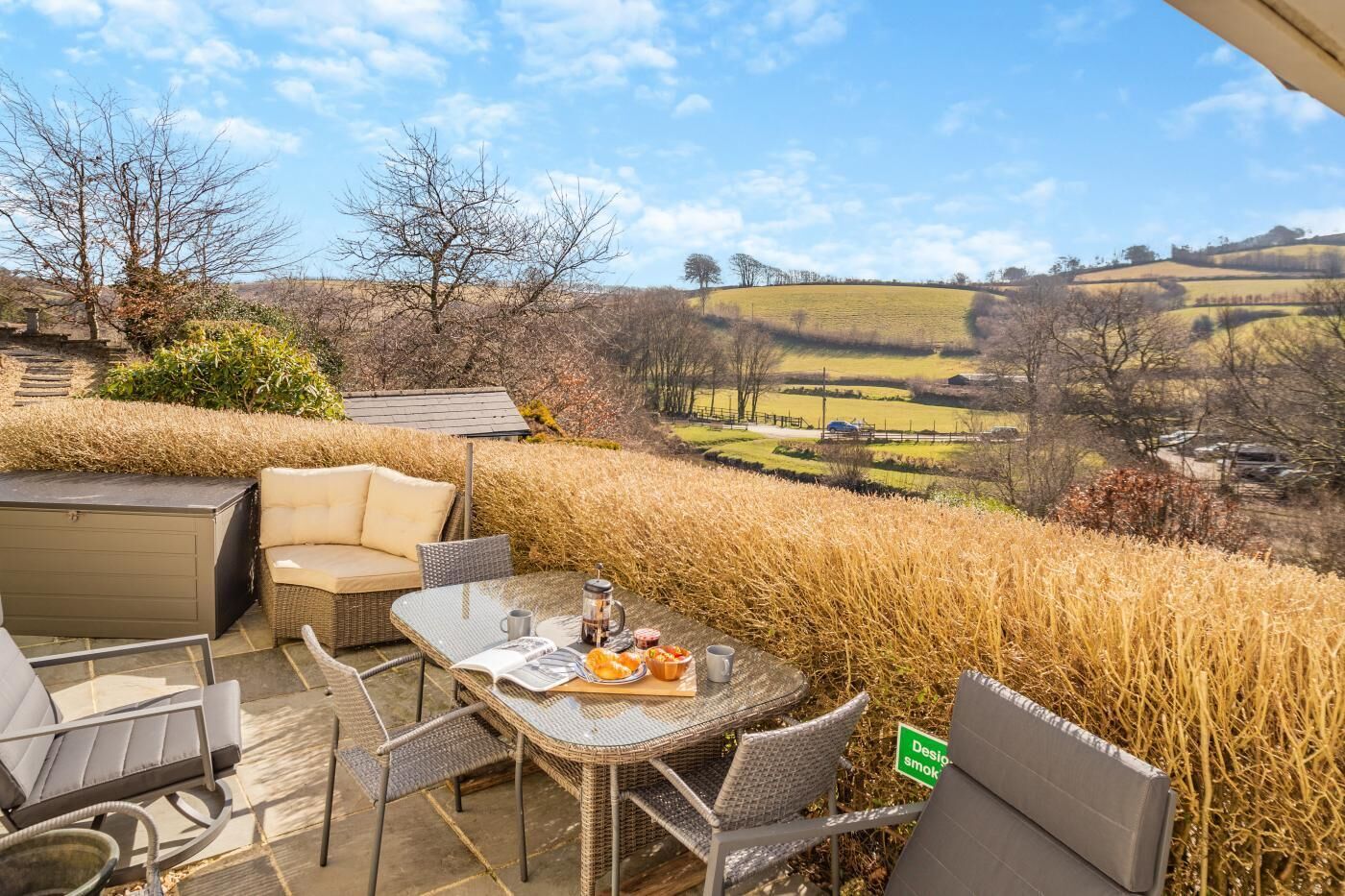 An outdoor seating area with a table, chairs, and a view of rolling hills.
