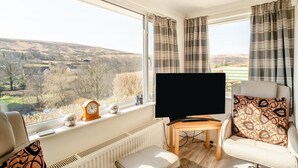 A living room with a large window, a flat-screen TV, a wooden coffee table, and a sofa. - 2 Bed in Withypool (oc-c30940) (Withypool)
