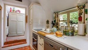 Een keuken met witte kastjes, een houten aanrechtblad en een raam met gordijnen.