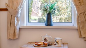 A window with curtains, a vase with greenery, a teapot, a mug, and pastries on a wooden table. - 2 Bed in Welney (oc-o30872) (Welney)