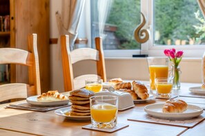 A breakfast table with pancakes, croissants, and orange juice glasses.