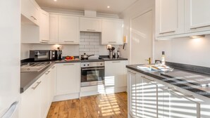 A modern kitchen with white cabinets, stainless steel appliances, and a wooden floor. - 2 Bed in Welney (oc-o30872) (Welney)