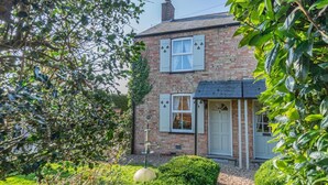A two-story brick house with a white door and shutters, surrounded by greenery and a well-maintained garden. - 2 Bed in Welney (oc-o30872) (Welney)