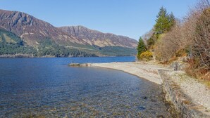 A lake with a rocky shoreline and mountains in the background.