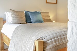 Ein Bett mit gesteppter Bettdecke, einem Holz-Kopfteil und mehreren Kissen.
