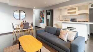 A modern living room with a grey sofa, a wooden coffee table, and a dining area with a round table and chairs. - |EP| Nice Apt w/View, Balcony & Gym in El Poblado (Medellín)