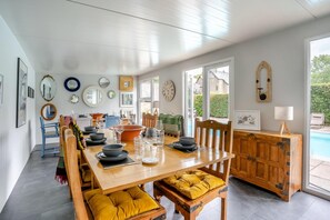 Un espace repas avec une table en bois, des chaises et une vue sur l’extérieur.