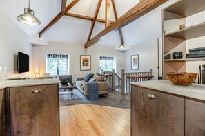A spacious kitchen with wooden beams, a dining area with a sofa, and a staircase leading to another level.