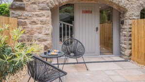 An outdoor seating area with stone walls, a door with a sign, and a small table with chairs. - 1 Bed in Nant-y-derry (oc-g30807) (Nant-y-derry)