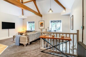 A spacious living area with a sofa, a table with bowls, a TV, and a staircase with a railing. - 1 Bed in Nant-y-derry (oc-g30807) (Nant-y-derry)