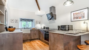 A modern kitchen with a central island, built-in appliances, and a large window. - 1 Bed in Nant-y-derry (oc-g30807) (Nant-y-derry)