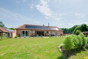 A brick house with a tiled roof, a covered patio, and a well-maintained lawn. - 2 Bed in Moulton St. Mary (oc-c30849) (Moulton Saint Mary)