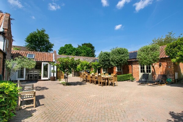 A courtyard with a brick patio, outdoor seating, and brick buildings with tiled roofs. - 6 Bed in Walsingham (oc-r30797) (Little Walsingham)