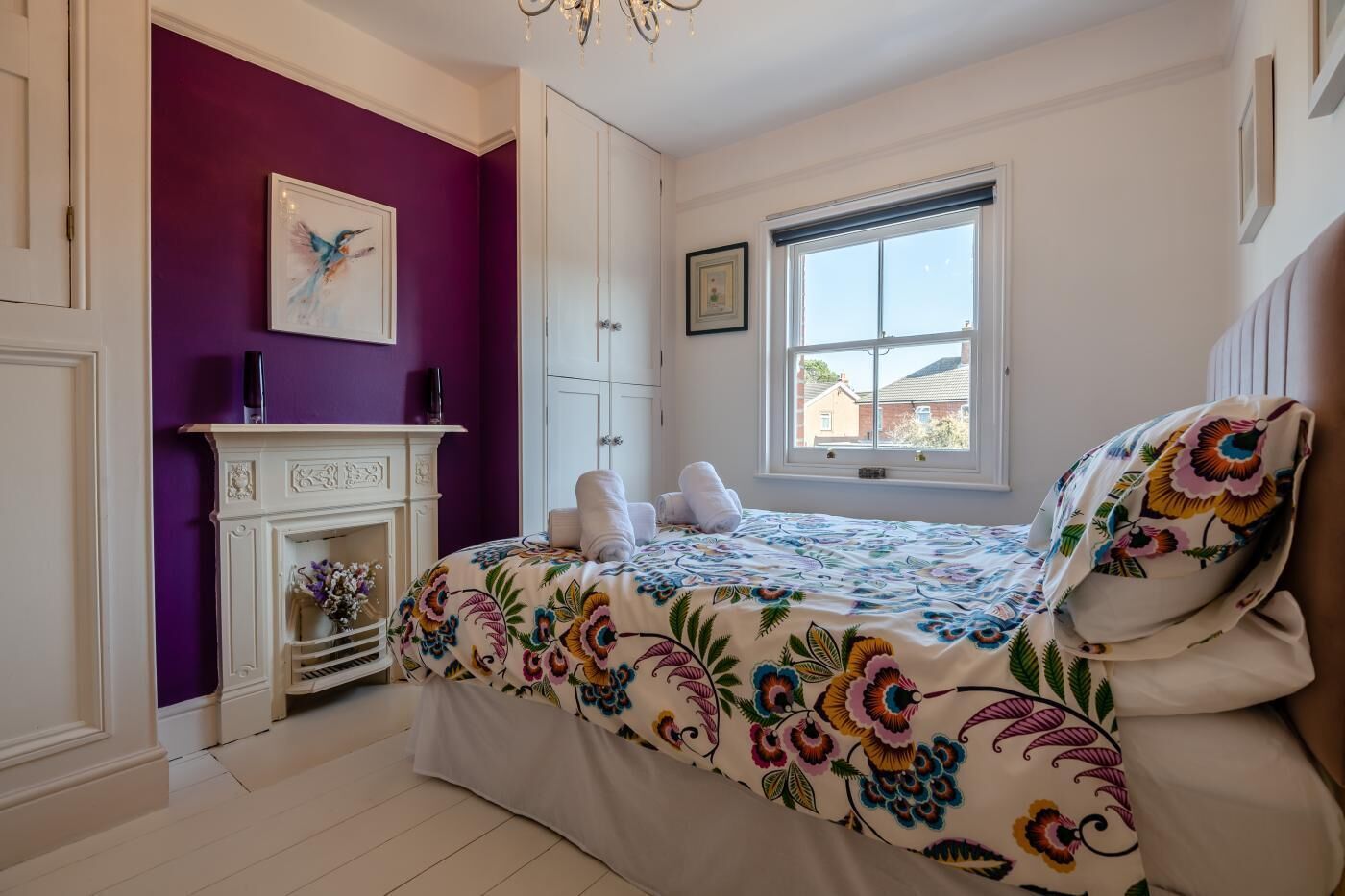 Een slaapkamer met een bed, een open haard, een raam en een deur.