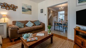 A cozy living room with a brown sofa, a coffee table with a teapot and a tray, and a TV on a wooden stand. - 2 Bed in Wimborne (oc-s30924) (Wimborne)