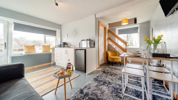 Un apartamento moderno con cocina, comedor y sala de estar. Cuenta con una escalera, un sofá y una mesa de centro.
