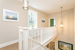 A staircase with white railings leading to an upper floor, a large window with a view of greenery, and a framed picture on the wall. - 1 Bed in Sutton-on-the-Forest (oc-t30950) (Sutton-on-the-Forest)