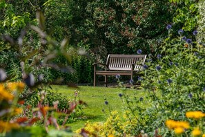 A bench in a garden with various plants and flowers. - 1 Bed in Sutton-on-the-Forest (oc-t30950) (Sutton-on-the-Forest)