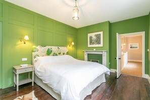 A bedroom with a bed, bedside tables, a fireplace, and a door leading to another room. - 1 Bed in Sutton-on-the-Forest (oc-t30950) (Sutton-on-the-Forest)