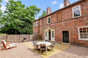A brick house with a patio, outdoor seating, and a large tree. - 1 Bed in Sutton-on-the-Forest (oc-t30950) (Sutton-on-the-Forest)
