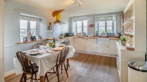 Una cucina moderna con pensili in legno, un tavolo da pranzo per sei persone e una macchina per il caffè.