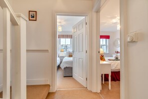 A hallway leading to a bedroom with a bed, a bedside table, and a window with a view of the city. - 2 Bed in Whitby (oc-m30865) (Whitby)