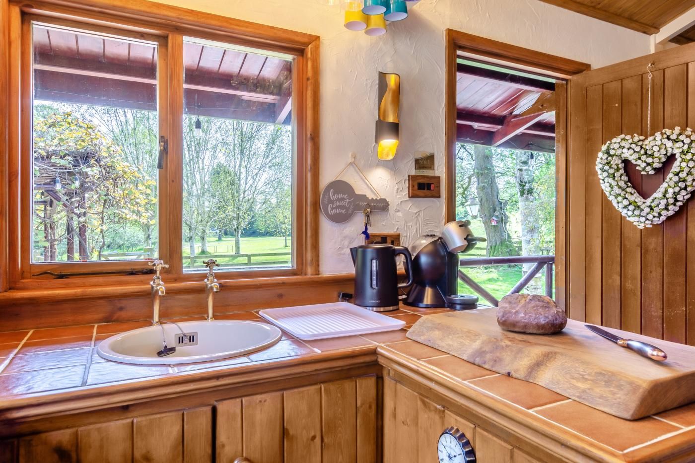 A rustic kitchen with a wooden countertop, a sink, and a clock.