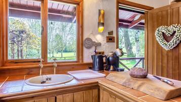 A rustic kitchen with a wooden countertop, a sink, and a clock.
