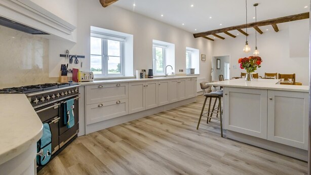 Una cocina amplia con una isla grande, vigas de madera y vistas al exterior.