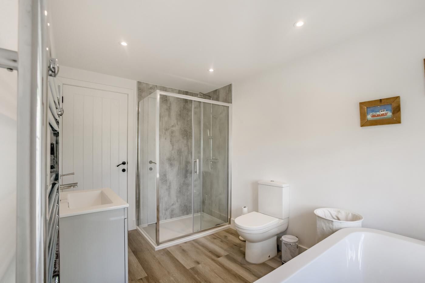 Een moderne badkamer met een douchecabine van glas, een toilet, een bad en een wastafel.