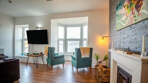 Una sala de estar con chimenea, un televisor de pantalla plana y un ventanal grande.