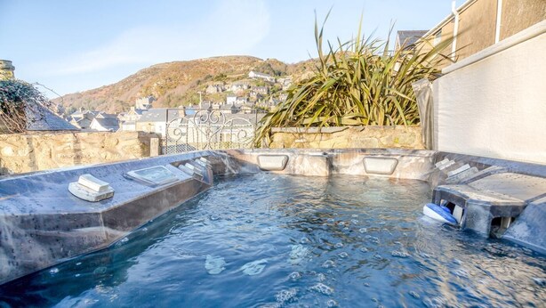 Un jacuzzi con escalones, una piscina y vistas a un pueblo en la ladera.