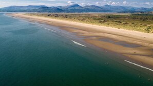 Paisaje costero con playa, cielo despejado y montañas a lo lejos.