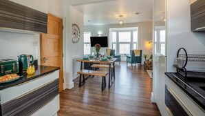 Una cocina moderna con comedor, suelo de madera y un amplio ventanal que proporciona luz natural.
