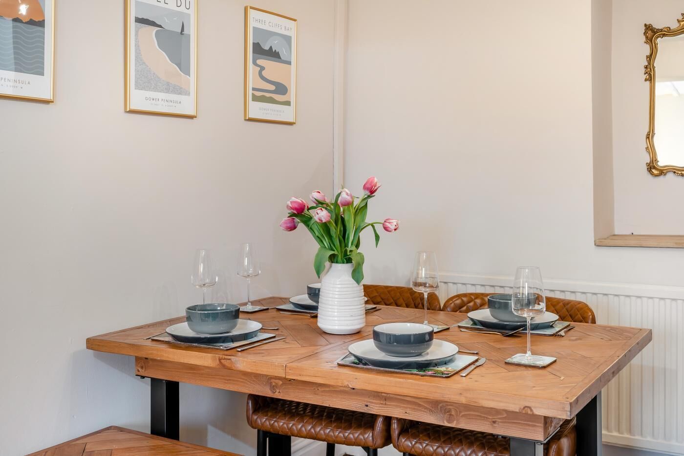 A dining table set with plates, bowls, and glasses, accompanied by a vase of flowers.