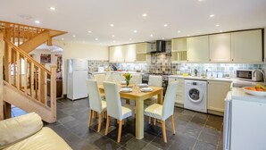 Une cuisine moderne avec un coin repas, un lave-linge et un escalier.